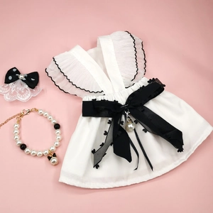 Detailed set featuring white lace pet dress, black polka dot clip, and pearl necklace