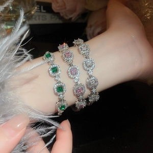 Macro shot of geometric emerald and pink crystal links with diamond pavé accents