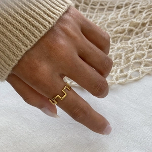 Detail of irregular geometric gold stainless steel ring worn on hand with knit background