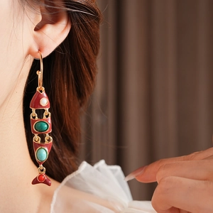 Gros plan de boucles d'oreilles poisson vintage dorées avec émail rouge et pierres