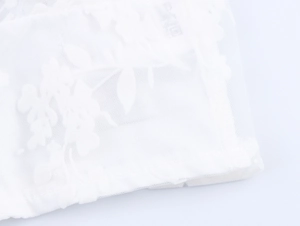 Macro shot of white sheer mesh top with delicate floral lace embroidery details