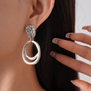 Gros plan de boucles d'oreilles pendantes géométriques argentées à texture martelée
