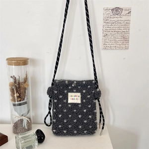 Detail view of plush fleece crossbody bag with white polka dots and woven strap