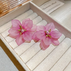 Macro shot of pink floral resin earrings with golden pistils and pearls in a velvet box