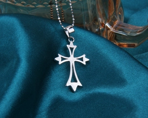 Détail du pendentif croix évidée en argent sterling S925 sur fond de soie élégant