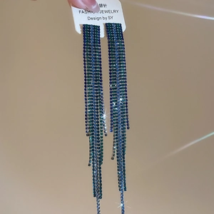 Detail of silver needle earrings featuring blue and green rhinestone fringe tassels