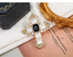Detail view of a vintage Baroque gold cross brooch with black and white crystals