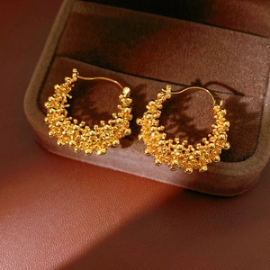 Détail de boucles d'oreilles créoles plaquées or 18k avec surface perlée sur du velours