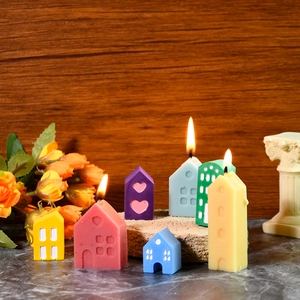 Miniature colorful house-shaped candles on stone base with warm aesthetic background