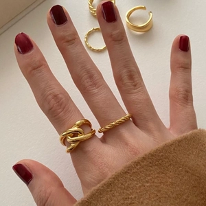 Detailed close-up of gold chain link and spiral twisted rings worn on model fingers