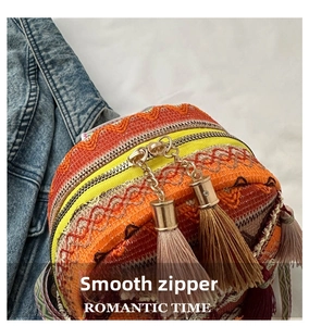 Detail of bohemian woven backpack featuring smooth dual metal zippers and brown tassels