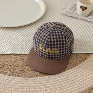 Detailed top view of a brown plaid baseball cap featuring gold Kindness Club embroidery