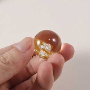 Macro shot of an amber resin sphere with white floral inclusions and a smooth surface