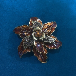 Vintage gold flower brooch with brown petals and rhinestones on a navy velvet background