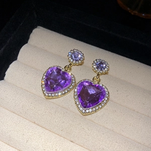 Detail of vintage gold bow earrings featuring large purple heart-shaped crystals