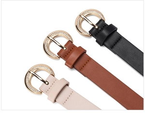 Close-up of three elegant leather belts in black, brown, and beige with rhinestone buckles