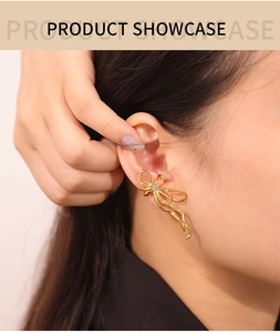 Close-up of golden bow-shaped titanium steel earring with white zircon inlay on model