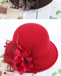 Close-up of elegant red wool felt hat with mesh veil, feathers and floral detail