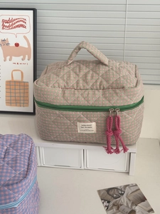 Detail of quilted plaid cosmetic bag featuring green zipper and pink woven rope puller
