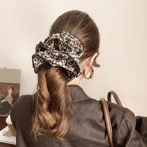 Detailed view of a layered leopard print scrunchie in coffee silk with black piping finish
