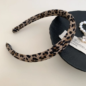 Detail of leopard print fabric headband on a black tray with elegant pearls and accessories