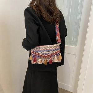 Detailed back view of a colorful bohemian envelope bag with tassels and woven strap