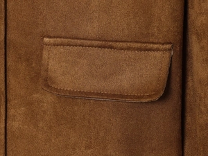 Macro view of dark brown suede jacket detail showing pocket and premium stitching