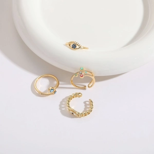 Set of 4 gold-plated evil eye rings with chain design and enamel details on white surface