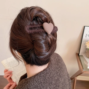Detailed view of a brown plush heart hair clip used in an elegant updo hairstyle