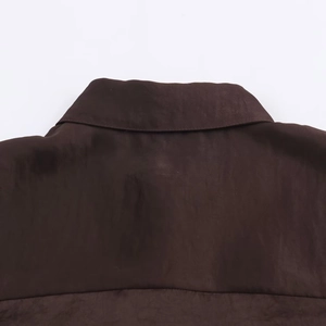 Dettaglio macro del colletto della camicia in raso marrone scuro con cuciture fini