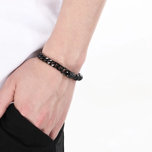 Detail of men's black beaded bracelet with skull charm and cuban link chain