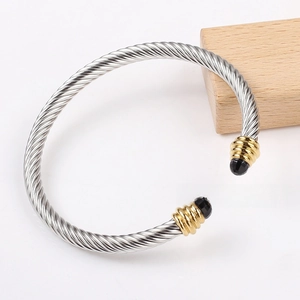 Macro detail of silver cable twist bangle with gold accents and black gemstone ends