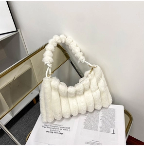 Detail of white faux fur handbag with knotted strap on a golden frame chair