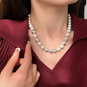 Detail of elegant pearl and silver bead necklace worn on model with red knitwear