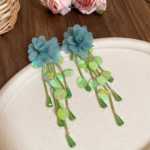 Detail of light blue chiffon flower earrings with long sequin tassels and green beads