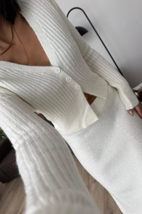 Dettaglio della trama in maglia a coste bianca del cardigan con scollo a V e gonna