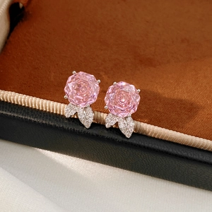 Vista macro di orecchini a rosa in zirconia rosa con foglie pavimentate su velluto