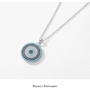 Macro shot of silver Evil Eye pendant with blue and white zircon pavé settings