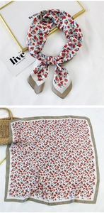 Detail of floral silk scarf with red and blue flowers and a khaki border flat lay