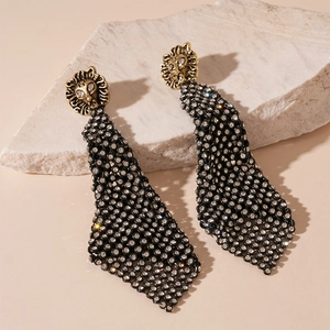 Close-up of vintage golden lion head earrings with black sequined fringe and rhinestones