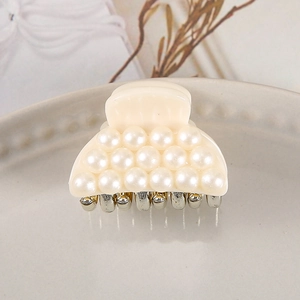 Detail of cream acrylic hair claw with pearl matrix and gold-tone metal teeth