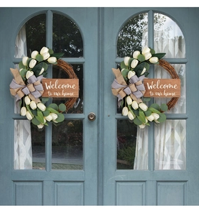 Detail of the wooden welcome sign and floral wreath on a vintage light blue door