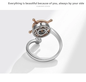 Close-up of rotatable golden ship wheel on a silver adjustable nautical spinning ring