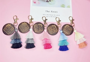 Detail of five wooden MAMA keychains featuring colorful layered tassels and golden clasps