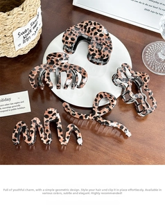 Detail of five leopard print hair claws in acetate finish on a white ceramic plate