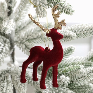 Red flocked Christmas reindeer ornament with gold glitter antlers on a snowy tree