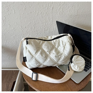 Détail du sac bandoulière matelassé beige avec pochette ronde sur un tabouret en bois