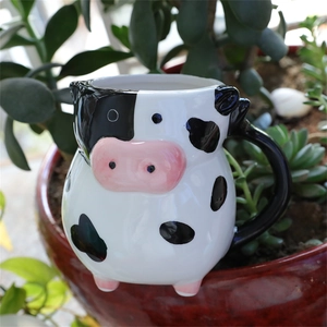 Detailed view of novelty cow-shaped ceramic mug placed in a succulent garden pot