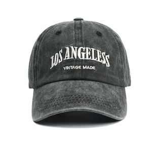Detailed view of white vintage embroidery on a washed dark gray cotton baseball cap