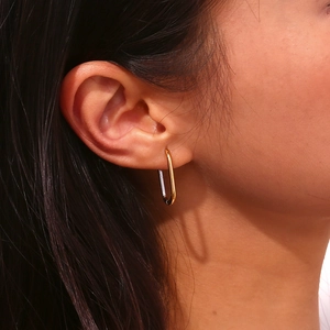 Close-up of elegant two-tone U-shaped earrings in gold and silver on female model
